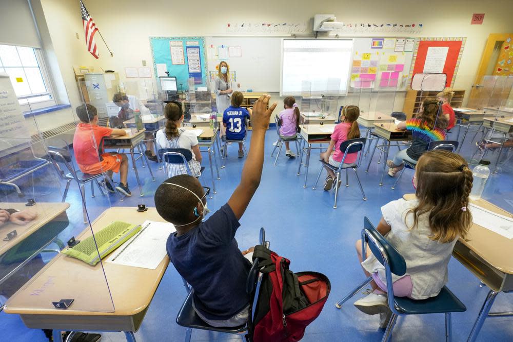 In this May 18, 2021, file photo, a teacher, center, and her third grade students wear face masks and are seated at proper social distancing spacing during as she conducts her class in Rye, N.Y. (AP Photo/Mary Altaffer, File)