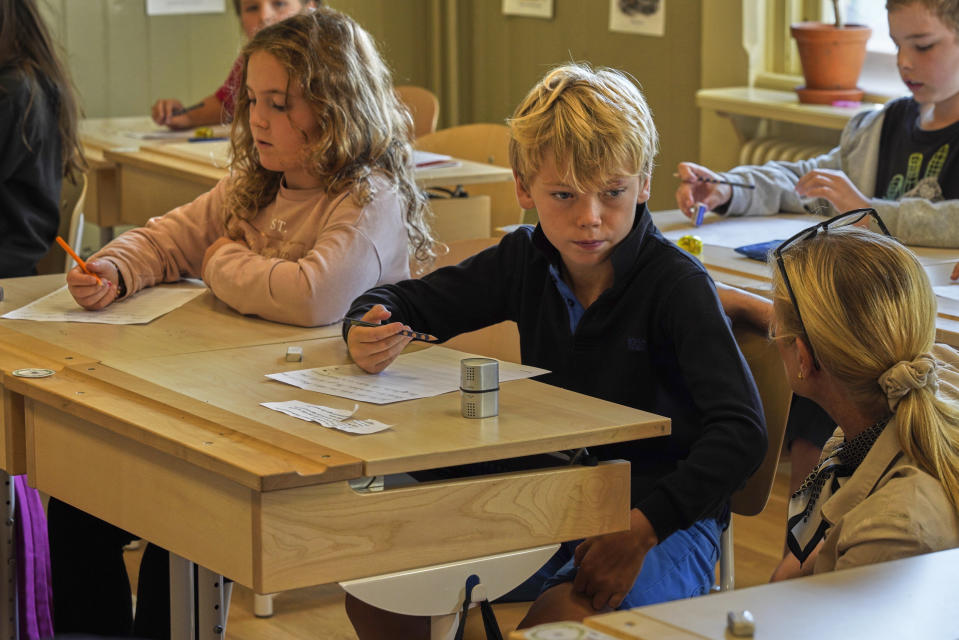 A teacher helps students practice their handwriting at the Djurgardsskolan elementary school in Stockholm, Sweden, Thursday, Aug. 31, 2023. As children across Sweden have recently flocked back to school after the summer vacation, many of their teachers are putting a new emphasis on printed books, quiet reading hours, and practicing handwriting as the country's yearslong focus on the digitalization of classrooms has come under scrutiny. (AP Photo/David Keyton)