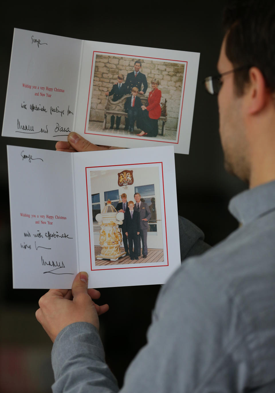 Auctioneer Paul Fairweather holds Christmas cards from 1991 (top) showing the Prince and Princess of Wales and their children; from 1997 the Prince of Wales and his two sons.