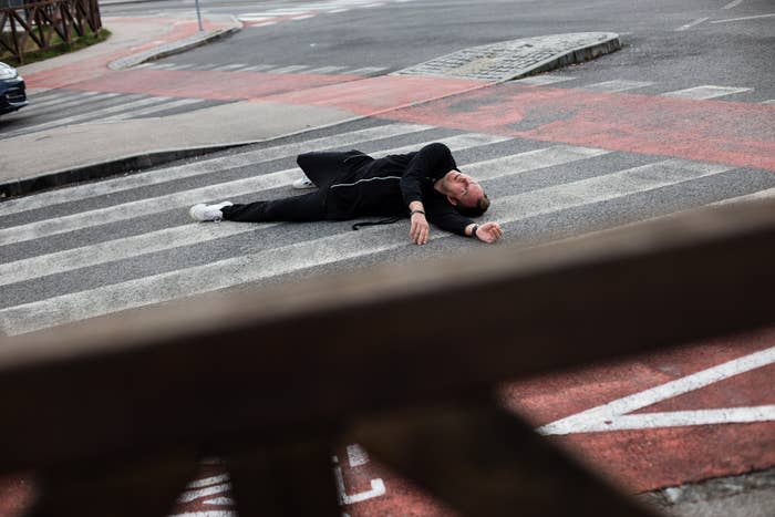 Person lying on a pedestrian crossing, appearing distressed or injured