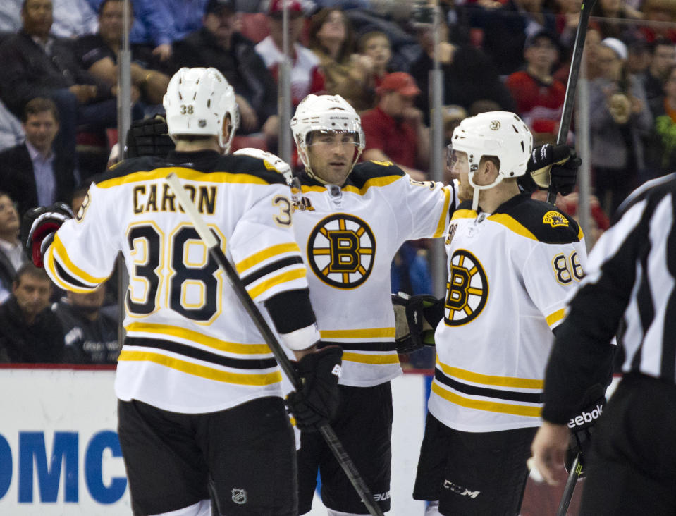 Boston Bruins defenseman Johnny Boychuk, center, celebrates his goal with forward Jordan Caron (38) and defenseman Kevan Miller, right, during the first period of an NHL hockey game against the Detroit Red Wings in Detroit, Mich., Wednesday, April 2, 2014. (AP Photo/Tony Ding)