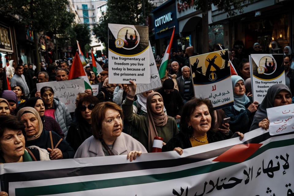 People in a crowd hold signs calling for a cease-fire in Gaza