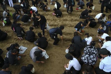 Thai people collect rice grains after the annual royal ploughing ceremony in central Bangkok, Thailand, May 12, 2017. REUTERS/Athit Perawongmetha