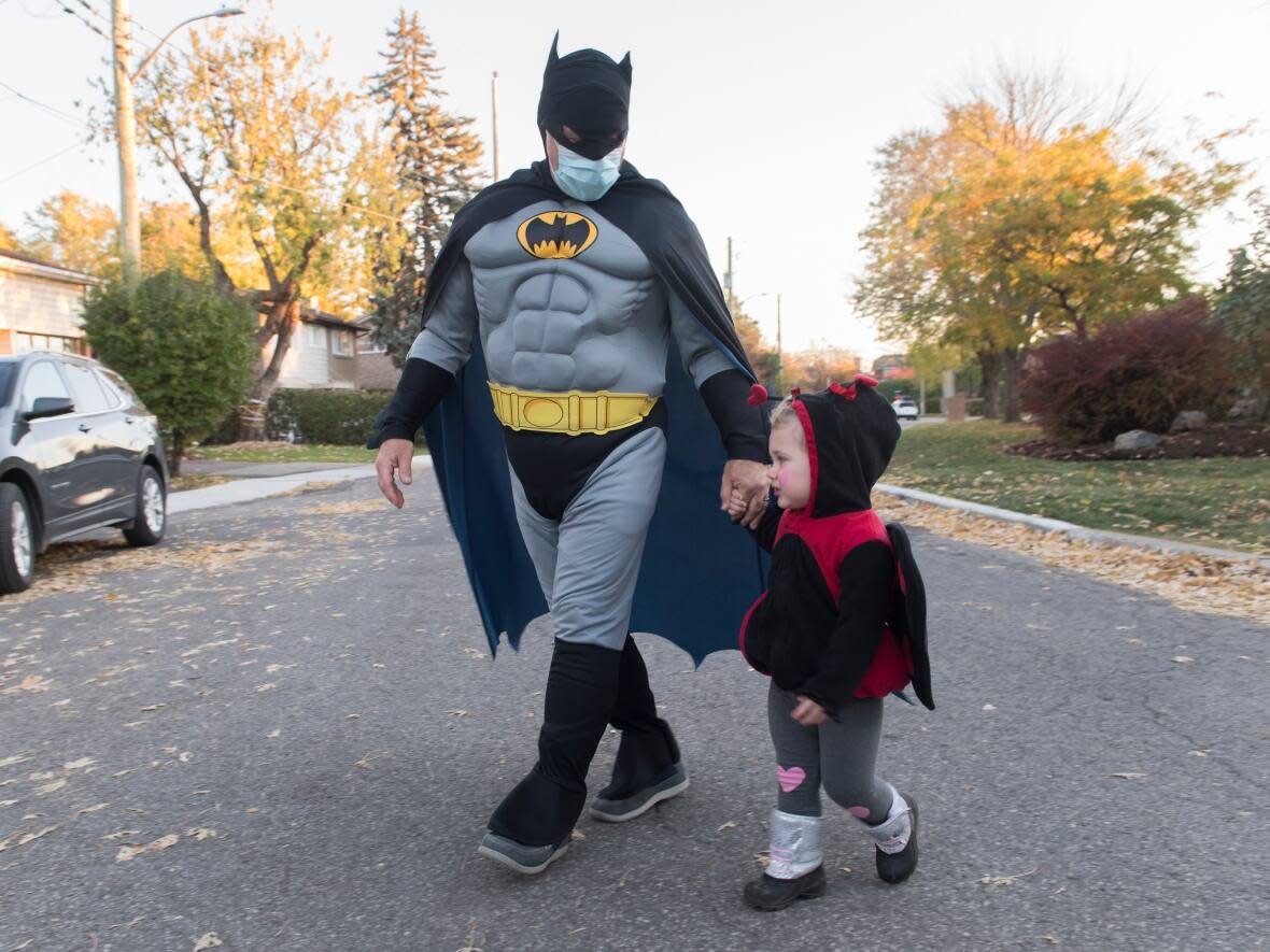 Marino Rossi and granddaughter Ruby Bishyk go trick-or-treating in Montreal last year during the COVID-19 pandemic. Ontario health officials have said trick-or-treating this year is generally safe, albeit with certain precautions. (Graham Hughes/The Canadian Press - image credit)