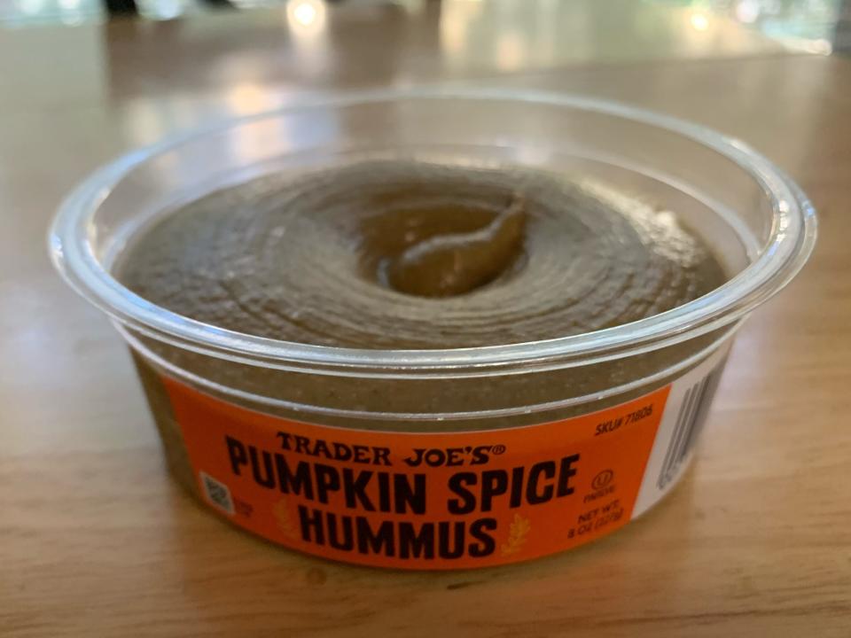 Clear container with orange label of Trader Joe's pumpkin-spice hummus on a wooden table