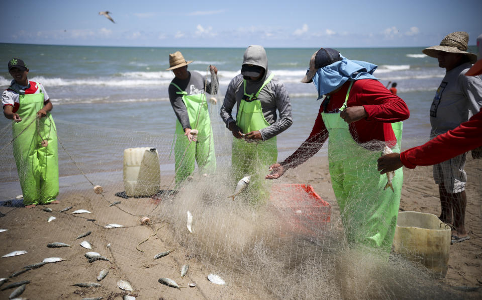 In this Aug. 3, 2019 photo, fishermen remove their catch from their nets at Playa Bagdad near the border city of Matamoros, Mexico. The origin of the town name Bagdad is lost in the mists of history. (AP Photo/Emilio Espejel)