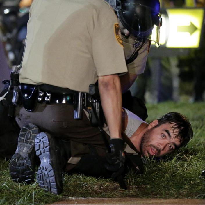 A man is detained by police during a protest Monday, Aug. 18, 2014, for Michael Brown, who was killed by a police officer Aug. 9 in Ferguson, Mo. Brown&#39;s shooting has sparked more than a week of protests, riots and looting in the St. Louis suburb. (AP Photo/Charlie Riedel)