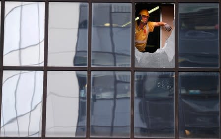 Workers repair windows which were damaged by protestors at the police headquarters in Hong Kong, China