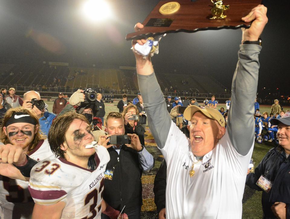 Killingly football coach Chad Neal raises the Class M state championship plaque as seniors Ryan Miller, left, and Jack Sharpe look on after Killingly's 28-14 win over Rockville in 2021 at Veterans Memorial Stadium in New Britain.