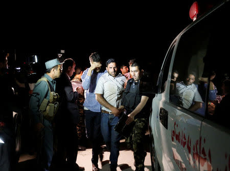 Afghan men walk towards an ambulance after they were rescued from the site of an attack at American University of Afghanistan in Kabul, Afghanistan August 24, 2016. REUTERS/Mohammad Ismail