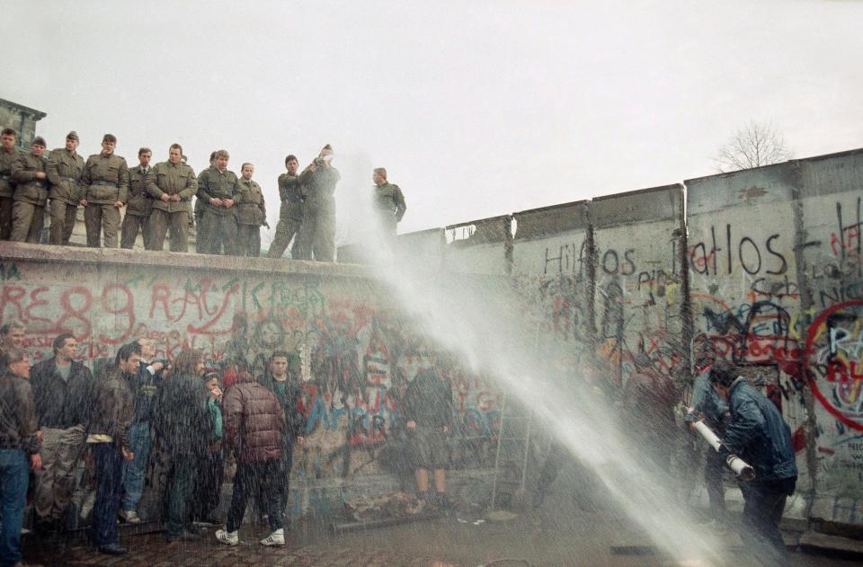 East German border guards use a hose to discourage West Berliners near Brandenburg gate, in Berlin on Nov. 11, 1989. The citizens from the west tried to demolish the wall, demanding it be pulled down.