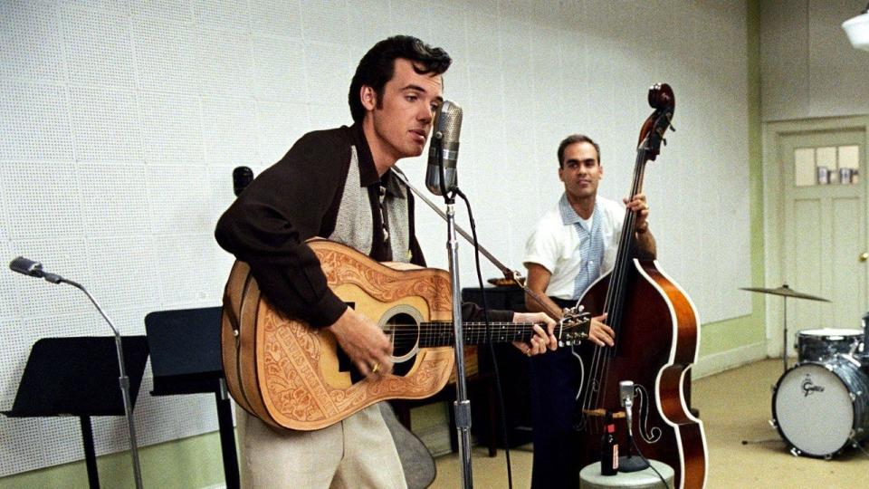 Tyler Hilton as Elvis Presley playing a guitar and singing into a microphone