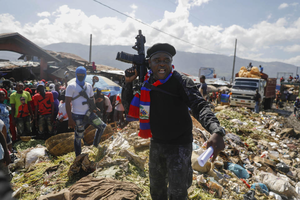 FILE - Jimmy Cherizier, also known as Barbecue, the leader of the "G9 and Family" gang, stands next to a garbage pile to call attention to the conditions people live in as he leads a march against kidnapping through La Saline neighborhood in Port-au-Prince, Haiti, Oct. 22, 2021. Cherizier is a former officer with Haiti's National Police who worked with the Departmental Crowd Control Unit, which is deployed when there are riots or protests and has been accused of excessive force. He has since become whom many consider Haiti's most powerful gang leader. (AP Photo/Odelyn Joseph, File)