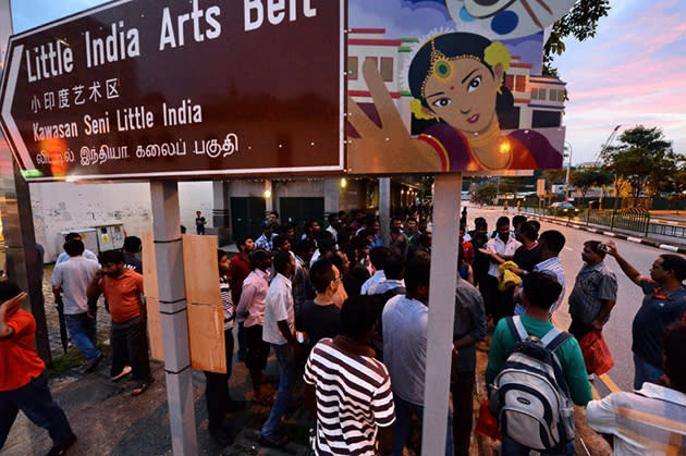 South Asian labourers stand outside a MRT train station after the suspension of sale and consumption of alcohol in the Little India district in Singapore on December 15, 2013. (AFP/Rosalan Rahman)