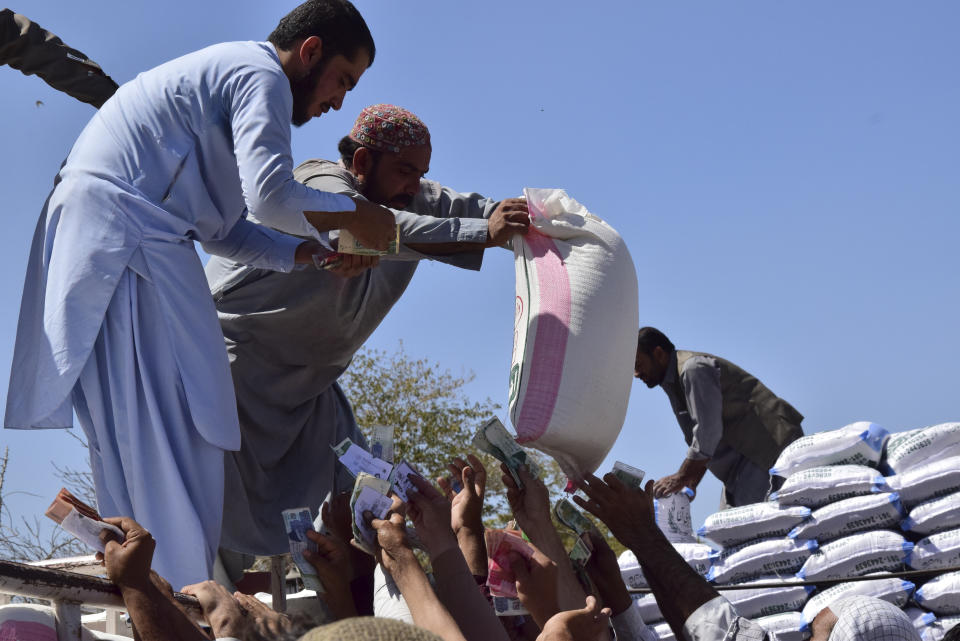 Flood victims jostle to buy flour in Quetta, Pakistan, Wednesday, Sept. 21, 2022. Devastating floods in Pakistan's worst-hit province have killed 10 more people in the past day, including four children, officials said Wednesday as the U.N. children's agency renewed its appeal for $39 million to help the most vulnerable flood victims. (AP Photo/Arshad Butt)