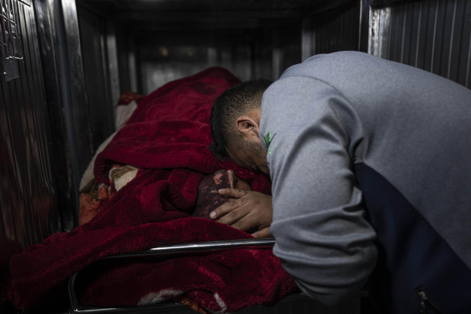 A mourner touches the body of a Palestinian killed in an Israeli airstrike, in the morgue of Al-Shifa Hospital in Gaza City, Tuesday, May 9, 2023. The Israeli military says it has killed three senior commanders of the militant Islamic Jihad group in targeted airstrikes. Palestinian health officials said 12 people were killed in total in Tuesday's attacks, including the commanders, their wives, several of their children and others nearby. (AP Photo/Fatima Shbair)