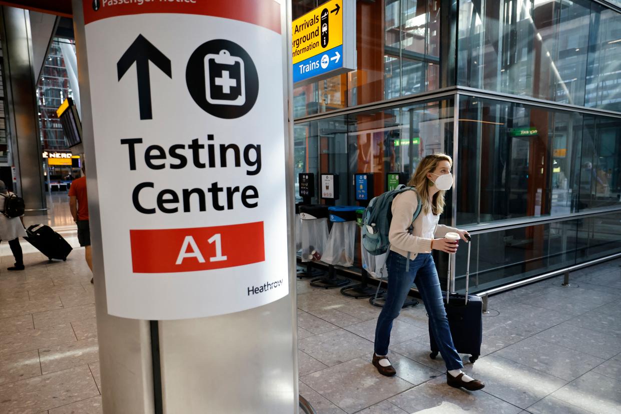 A traveller walks past a sign directing the public to a Covid testing centre at Terminal 5 in west London on August 2, 2021 as quarantine restrictions ease. - People fully vaccinated in the United States and European Union, except France will now be allowed to travel to England without having to quarantine on arrival. (Photo by Tolga Akmen / AFP) (Photo by TOLGA AKMEN/AFP via Getty Images)