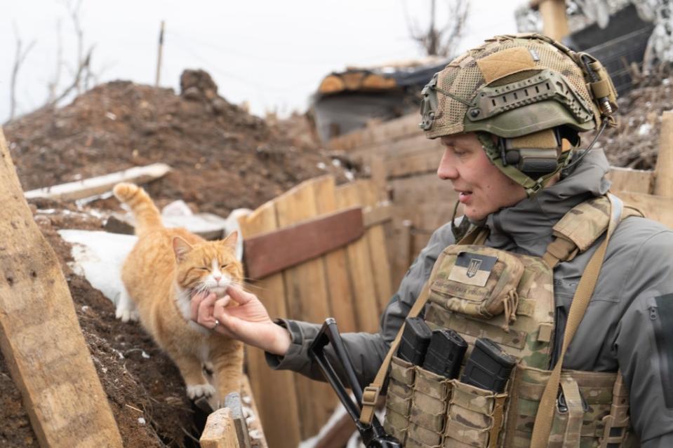 Zhenya pets Rizhyk, one of the cats living with the infantry on the zero line, 200 meters away from the Russians. Ukrainian soldiers often keep trench cats to hunt vermin and for emotional support. (Photo via Bennett Murray)