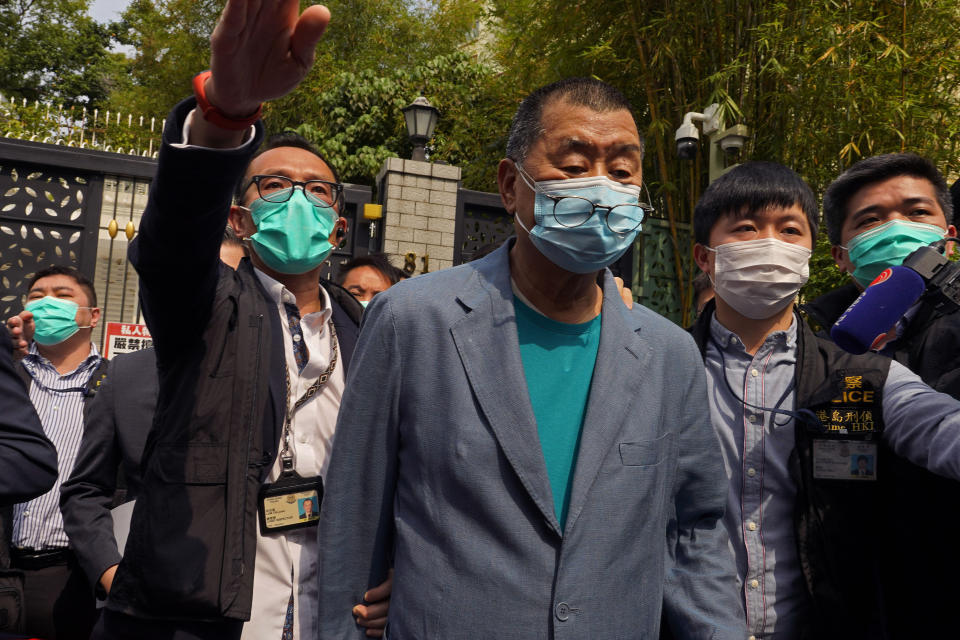 Hong Kong media tycoon Jimmy Lai, center, who founded local newspaper Apple Daily, is arrested by police officers at his home in Hong Kong, Saturday, April 18, 2020. Hong Kong police arrested at least 14 pro-democracy lawmakers and activists on Saturday on charges of joining unlawful protests last year calling for reforms. (AP Photo/Vincent Yu)