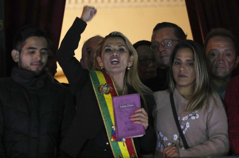 In this Nov. 12, 2019, AP file photo, the Senate's second vice president and opposition politician Jeanine Añez, center, wearing the presidential sash and carrying a Bible, addresses the crowd from the balcony of the Quemado palace after she declared herself interim president of the country, in La Paz, Bolivia. "The Bible has returned to the palace," she told allies and the media that night in contrast to Evo Morales' presidency that celebrated the country's indigenous religious beliefs. (AP Photo/Juan Karita)