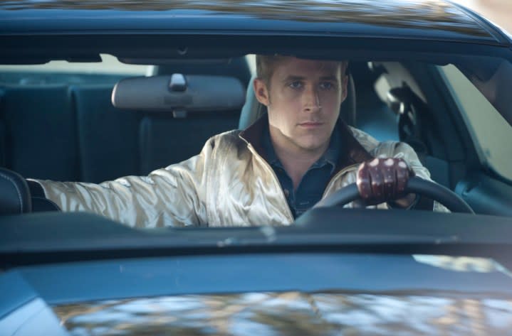 Ryan Gosling sits behind the wheel of a car.