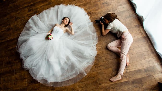 Young sexy woman photographer is taking pictures the bride in the studio.