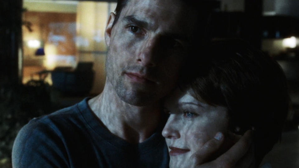 Tom Cruise and Kathryn Morris stand together in a dimly lit apartment in Minority Report.