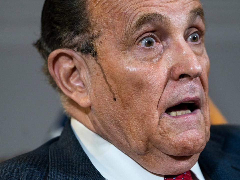 Hair dye runs down Rudy Giuliani’s cheek during a bizarre appearance at a press conference at which he was pushing false claims about the 2020 election (Getty)