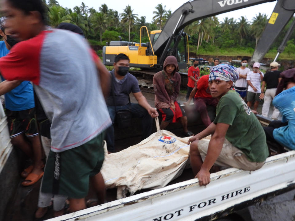 Rescuers sit beside a body bag containing the remains of a civilian victim when a Philippine military C-130 plane crashed in Patikul town, Sulu province, southern Philippines on Sunday July 4, 2021. A Philippine air force C-130 aircraft carrying combat troops assigned to fight Muslim militants crashed and exploded while landing in the south Sunday, killing dozens of army soldiers on board and three civilians on the ground in one of the worst disasters in the air force's history. (AP Photo/Nickee Butlangan)