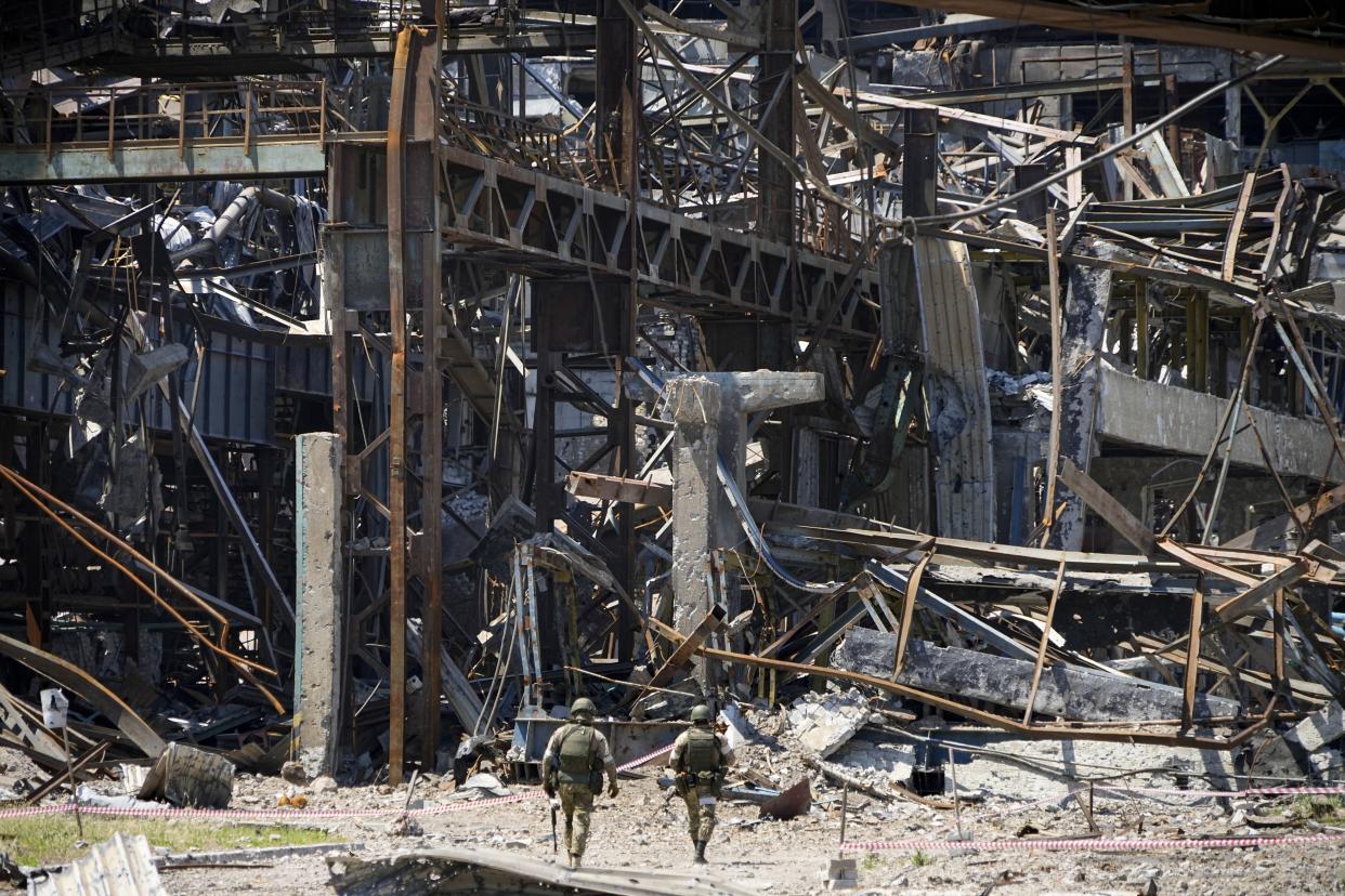 FILE - Russian soldiers walk through debris of the Metallurgical Combine Azovstal, in Mariupol, on the territory which is under the Government of the Donetsk People's Republic control, eastern Ukraine, Monday, June 13, 2022. Despite getting bogged down in Ukraine, the Kremlin has resisted announcing a full-blown mobilization, a move that could prove to be very unpopular for President Vladimir Putin. That has led instead to a covert recruitment effort that includes trying to get prisoners to make up for the manpower shortage. This photo was taken during a trip organized by the Russian Ministry of Defense. (AP Photo, File)