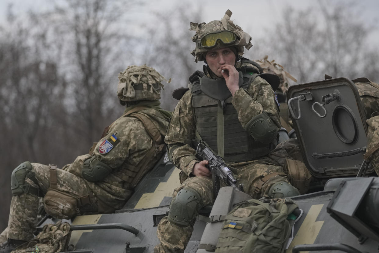 Ukrainian servicemen sit atop armored personnel carriers driving on a road in the Donetsk region, eastern Ukraine, Thursday, Feb. 24, 2022. Russian President Vladimir Putin on Thursday announced a military operation in Ukraine and warned other countries that any attempt to interfere with the Russian action would lead to "consequences you have never seen." (AP Photo/Vadim Ghirda)