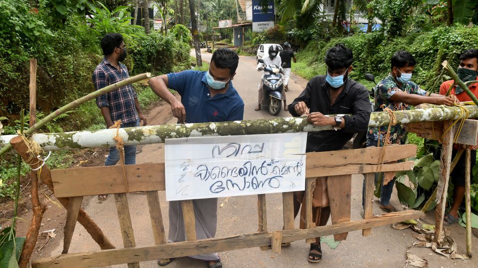 Residents fix a sign reading, "Nipah containment zone,"   in the Kozhikode district of Kerala, India, on September 13. - Stringer/Reuters