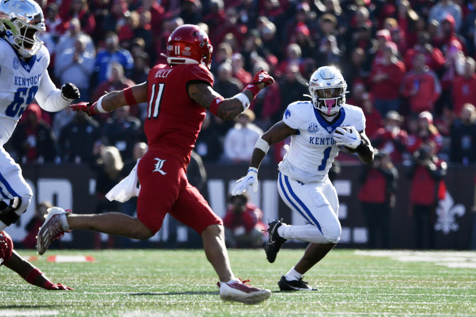 Kentucky running back Ray Davis (1) attempts to get away from Louisville defensive back Cam'Ron Kelly (11) during the second half of an NCAA college football game in Louisville, Ky., Saturday, Nov. 25, 2023. Kentucky won 38-31. (AP Photo/Timothy D. Easley)