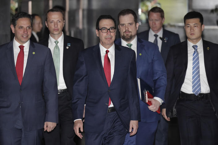 U.S. Treasury Secretary Steven Mnuchin, center, escorted by bodyguards and a delegation leaves a hotel in Beijing, Friday, March 29, 2019. U.S. trade negotiators lead by Mnuchin and Trade Representative Robert Lighthizer arrived in Beijing to start a new round of talks aimed at ending a tariff war over China's technology ambitions as officials hint they might be making progress. (AP Photo/Andy Wong)