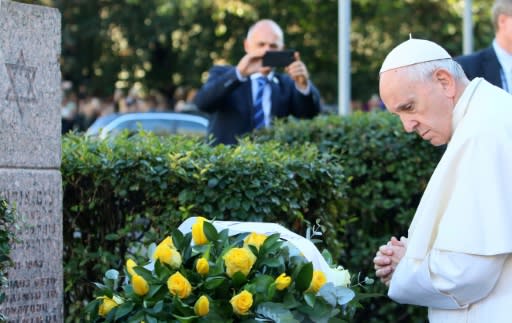 Pope Francis lays a bouquet of yellow roses at the foot of the Vilnius ghetto memorial and pays a silent tribute to Holocaust victims