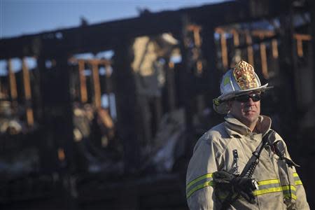 A firefighter stands in front of the charred remains of the Mariner's Cove Inn in Point Pleasant Beach, New Jersey, March 21, 2014. REUTERS/Charles Mostoller