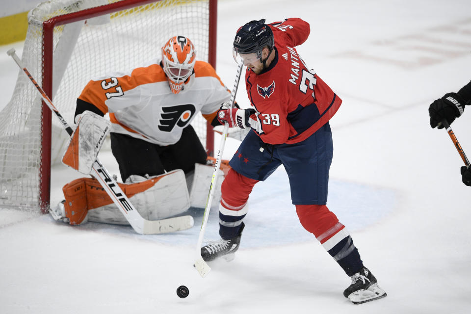 Washington Capitals right wing Anthony Mantha (39) handles the puck in front of Philadelphia Flyers goaltender Brian Elliott (37) during the first period of an NHL hockey game Tuesday, April 13, 2021, in Washington. (AP Photo/Nick Wass)