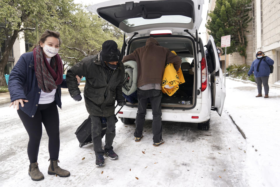 Morgan Handley, left, helps move people to a warming shelter at Travis Park Methodist Church to help escape sub-freezing temperatures, Tuesday, Feb. 16, 2021, in San Antonio. (AP Photo/Eric Gay)