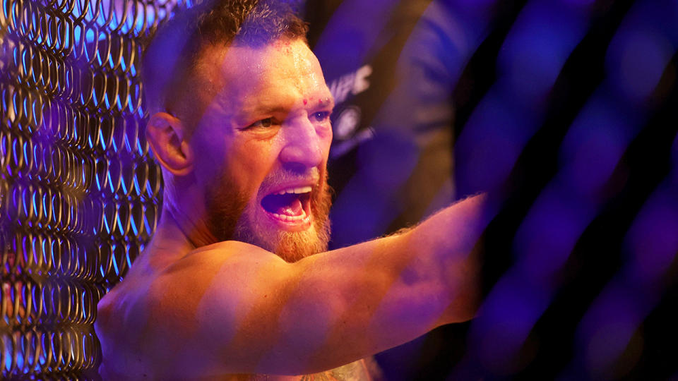 Conor McGregor gestures towards Dustin Poirier after breaking his ankle at UFC 264.