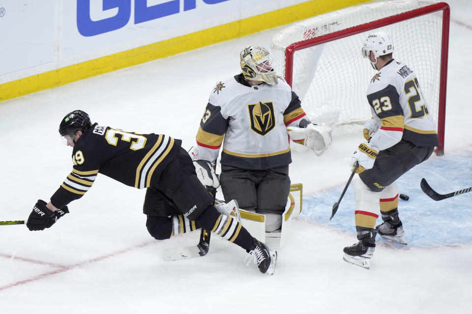 Boston Bruins center Morgan Geekie, left, hits the ice ah he scored in front of Vegas Golden Knights goaltender Adin Hill, center, and defenseman Alec Martinez, right, in the second period of an NHL hockey game, Thursday, Feb. 29, 2024, in Boston. (AP Photo/Steven Senne)