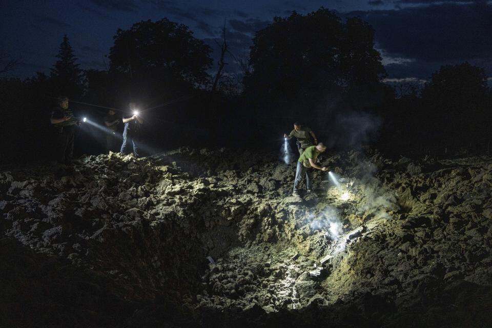 Ukrainian policemen looking for fragments of a rocket in a crater after a Russian attack on a residential neighbourhood in Pokrovsk, Ukraine, Wednesday, June 21, 2023. (AP Photo/Evgeniy Maloletka)