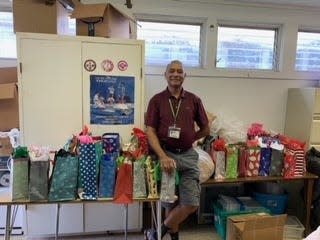 Tom Butler, employee for Marion County Schools who serves as liaison for the homeless children of Marion County, stands with the 32 Christmas bags filled with pajamas and books totaling $700 in donations donated by the GFWC Greater Ocala Woman's Club.