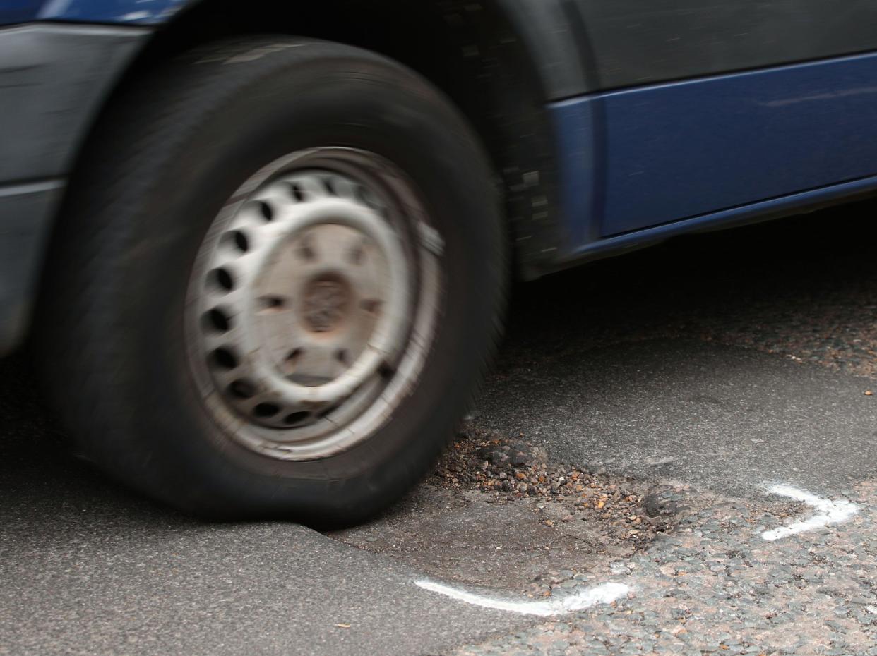 File photo dated 11/5/2018 of a car hitting a pothole on a road. Drivers are being urged to report every road surface crack 