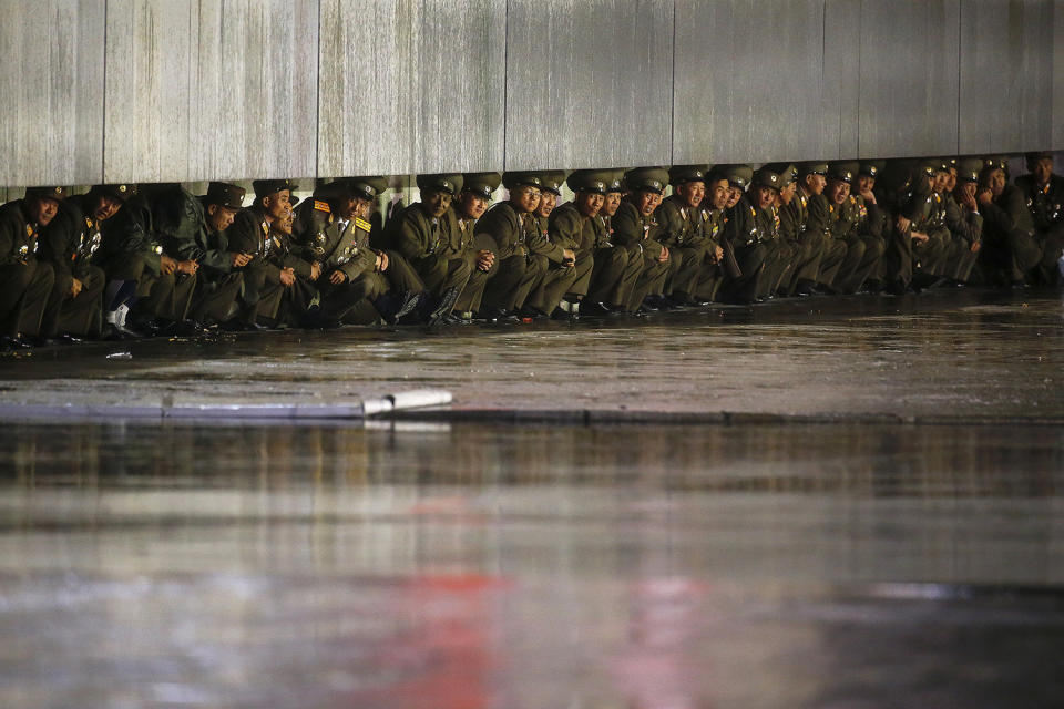 North Korean officers shield themselves from the rain