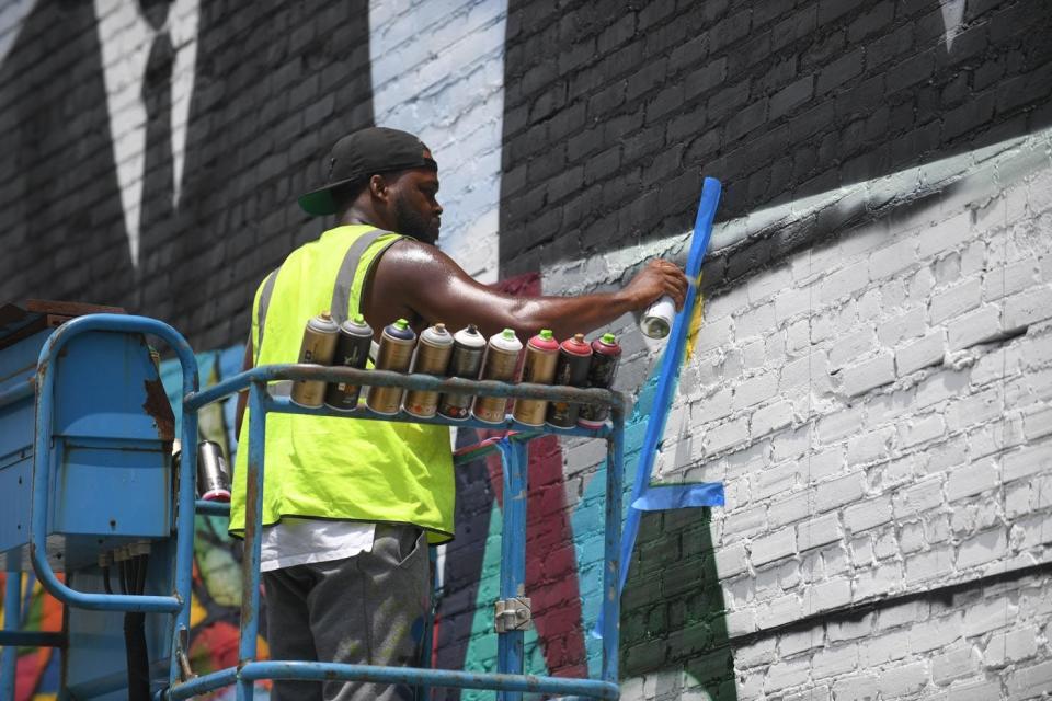 Paul Boyd III, works on a community-themed mural at the corner of East Church Street and Route 13 in Salisbury, Md. on Wednesday, July 11, 2019.