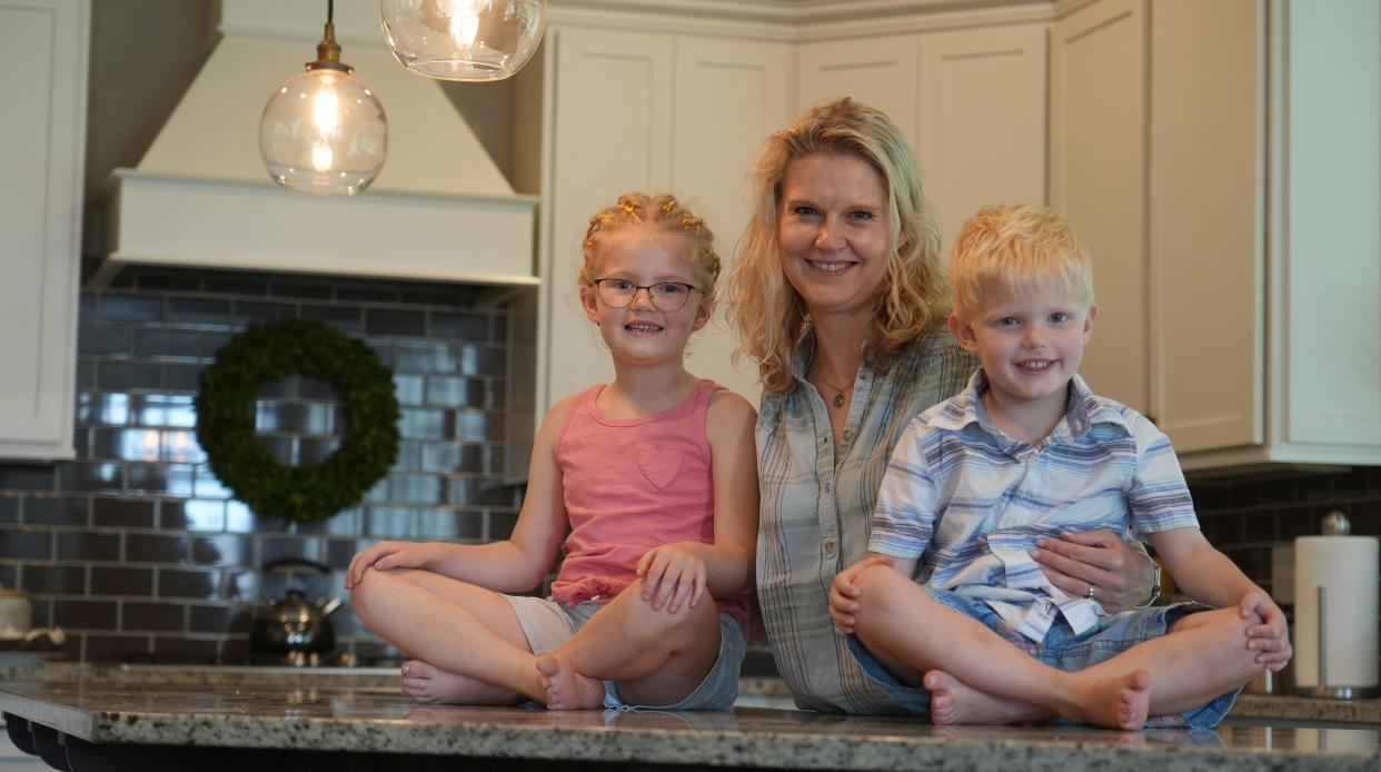 Jenn Atwood, a Columbus-area resident, holds her children Grace, 7, and Theo, 5, in their kitchen. Grace, a student in Olentangy schools, attends off-site Bible study during school hours once week through LifeWise Academy. Supporters in several Northeast Ohio school districts, including Field, are trying to launch similar programs in their communities.