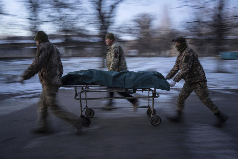 Ukrainian military medics haul a gurney with a body of their killed comrade into a morgue in Donetsk region, Ukraine, Monday, Jan. 9, 2023. (AP Photo/Evgeniy Maloletka)