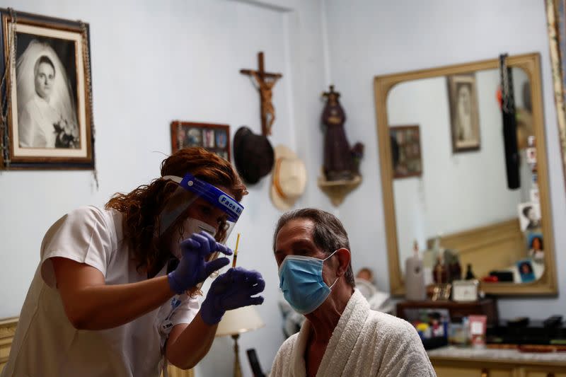 Comunidad de Madrid home care nurse Maria Jesus Santamaria explains patient Manuel Sanz how to take some medicine in his bedroom in Madrid