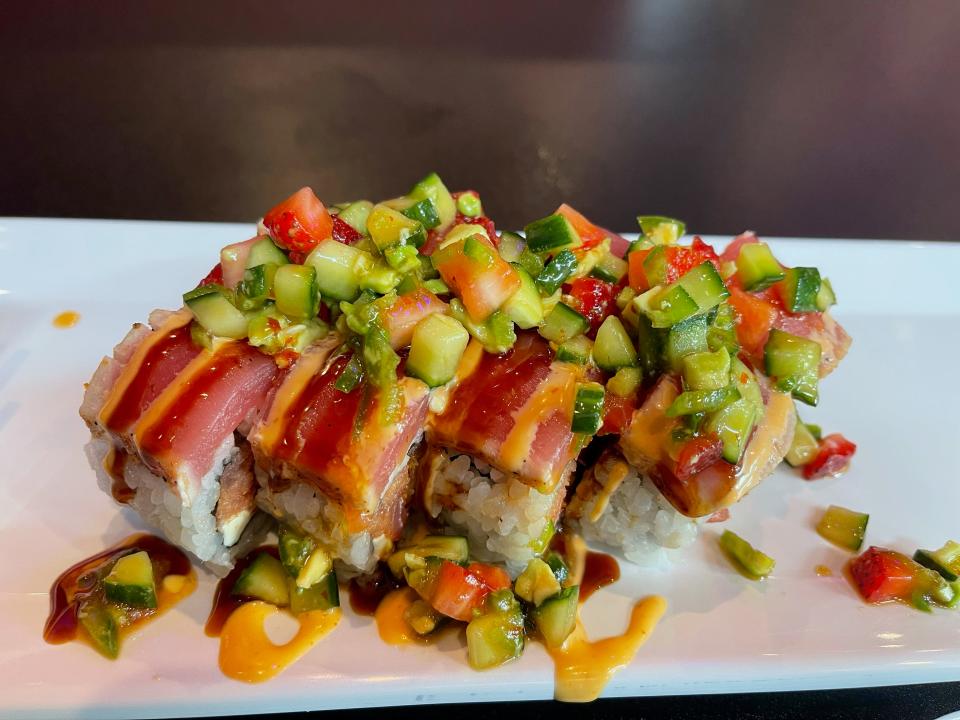 The Punk Rock Roll from Rock'n Roll Shushi features shrimp tempura, spicy tuna, cream cheese inside, seared tuna outside, topped with strawberry-avoca- do-jalapeño-cucumber salad, sweet-chili-ponzu dressing, spicy mayo and eel sauce.