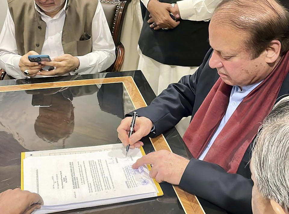 In this released by Pakistan Muslim League-N Party, Pakistan's former Prime Minister Nawaz Sharif, right, signs on the documents upon his arrival at Islamabad airport, Islamabad, Pakistan, on Saturday, Oct. 21, 2023. (Muslim League-N Party via AP)